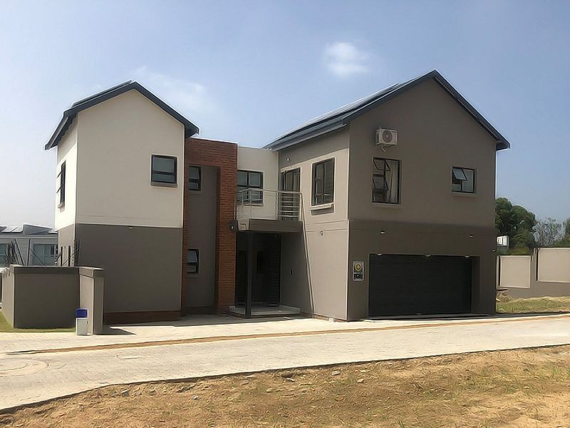 Modern double-story residential home featuring a double garage, balcony, and contemporary exterior finishes with solar panels installed on the roof.