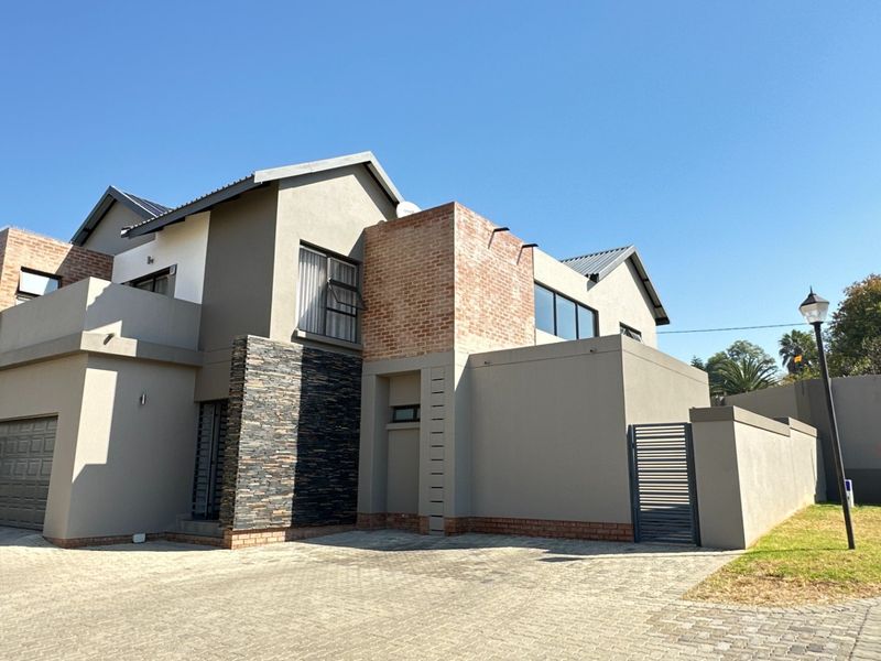 Modern double-storey residential property featuring a paved driveway, double garage, and a combination of stone and brick architectural detailing.