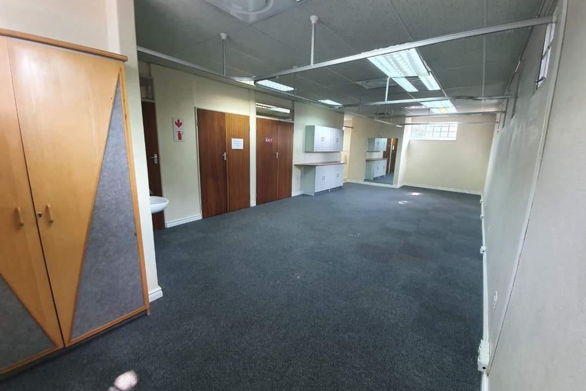 Spacious commercial office area featuring suspended ceilings, recessed lighting, built-in storage cabinetry, and a private basin.