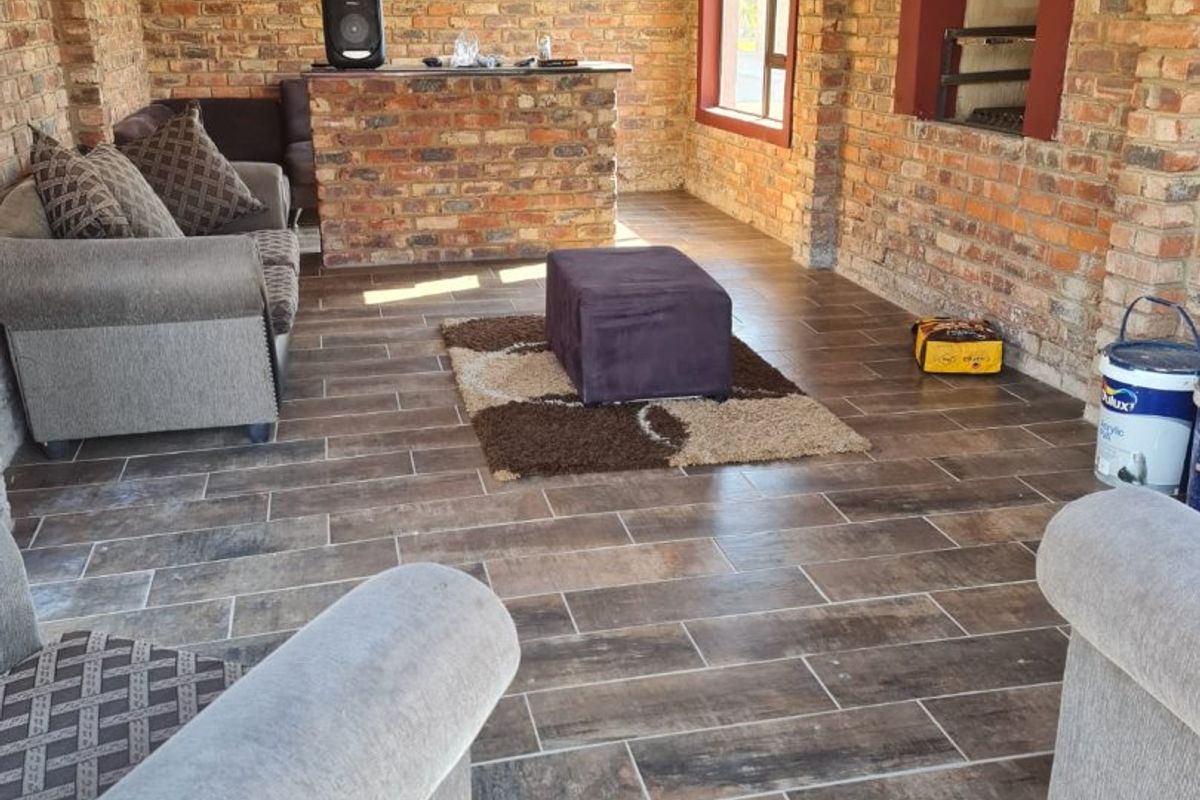 An enclosed patio area featuring exposed brick walls, tiled flooring, and a built-in braai, offering a rustic and functional entertainment space.