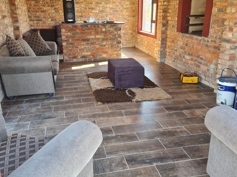 An enclosed patio area featuring exposed brick walls, tiled flooring, and a built-in braai, offering a rustic and functional entertainment space.