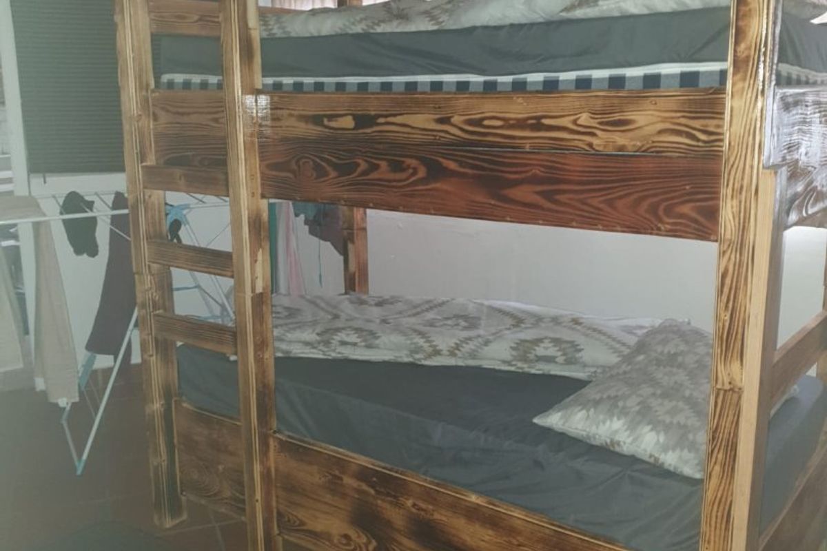 A bedroom featuring terracotta floor tiles and a vaulted ceiling, currently furnished with a wooden bunk bed.