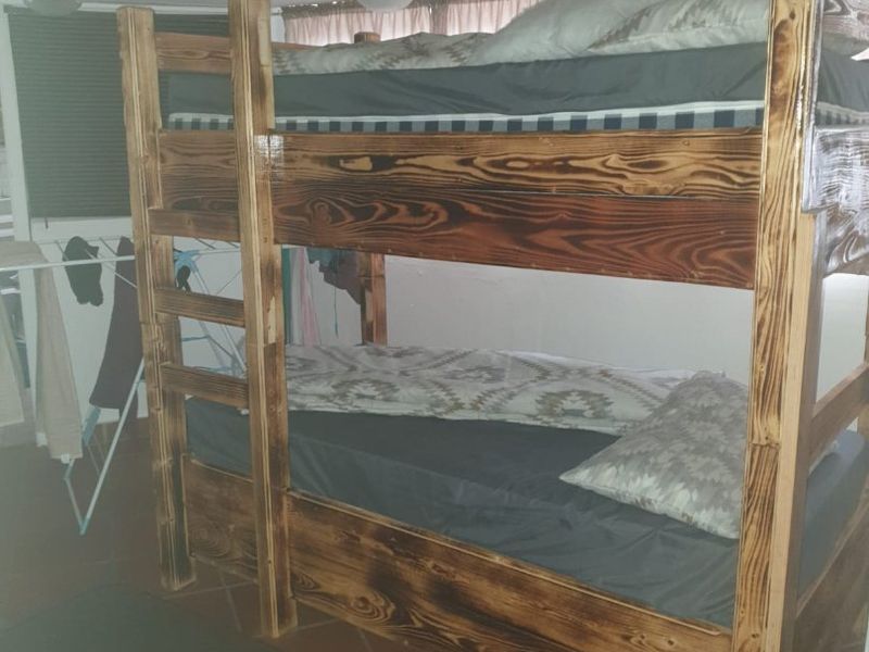 A bedroom featuring terracotta floor tiles and a vaulted ceiling, currently furnished with a wooden bunk bed.