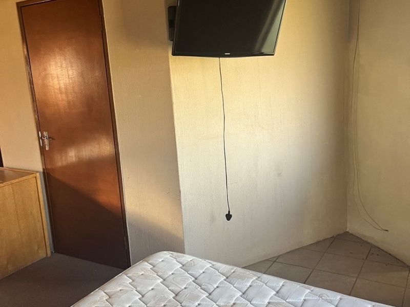 A bedroom featuring a traditional thatch roof, tiled flooring, and a wall-mounted television.