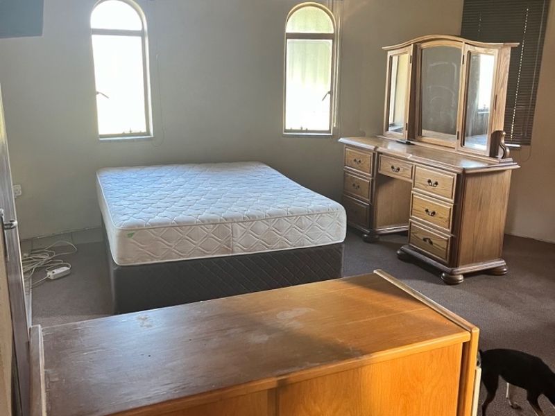 Spacious bedroom featuring a unique thatched roof ceiling, arched windows, and neutral wall finishes, offering a rustic aesthetic with potential for modernization.