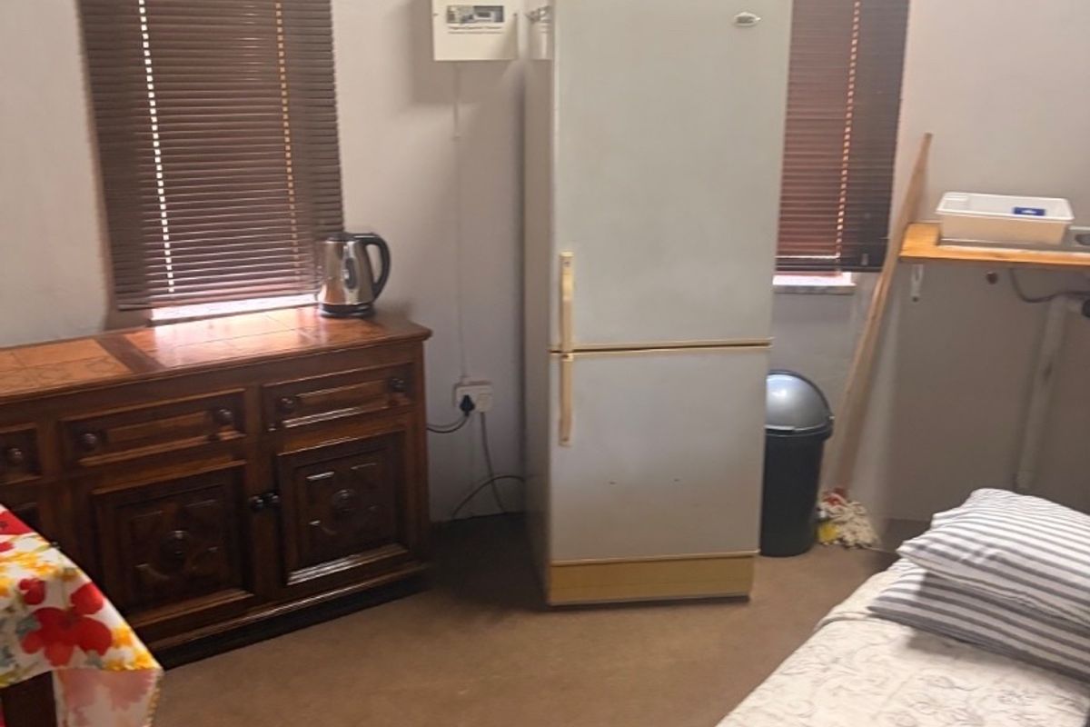 A bedroom featuring venetian blinds and an exposed electrical distribution board, requiring cosmetic updates to improve the overall finish and appeal.