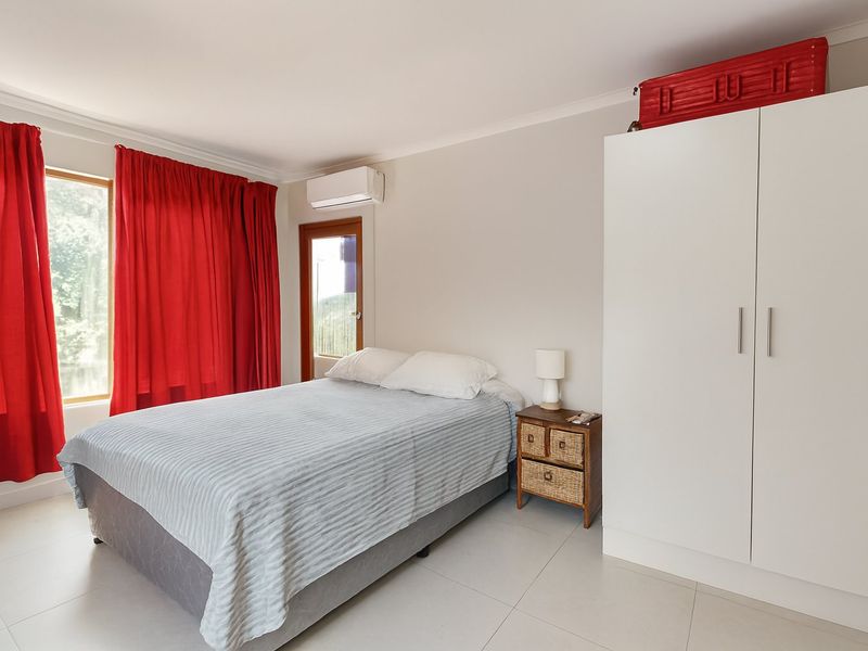 A bright bedroom featuring tiled flooring, a built-in wardrobe, and a wall-mounted air conditioning unit with access to an outdoor area.