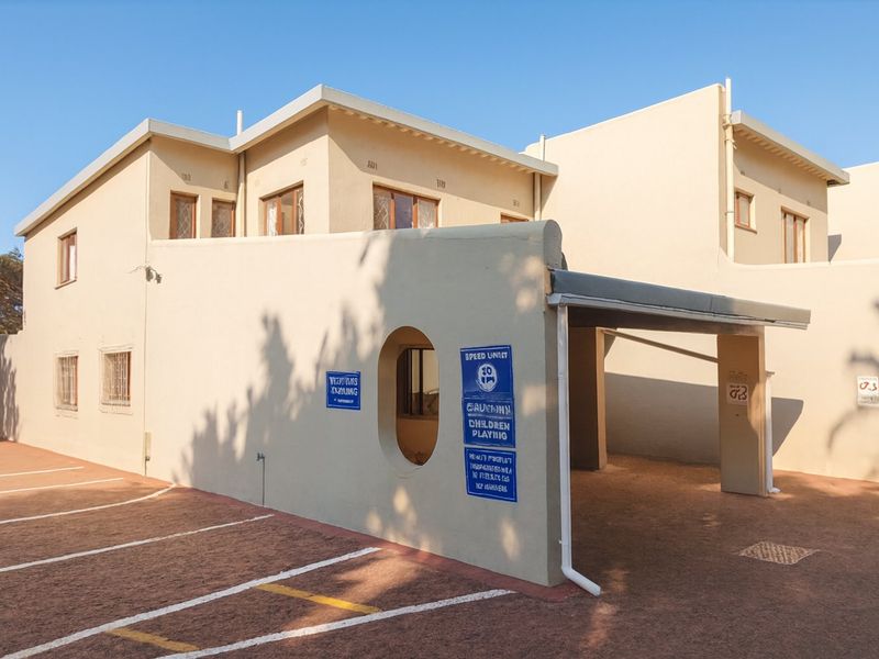 Exterior view of an apartment building featuring a covered carport, paved parking area, and secure window fixtures.