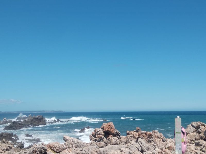 A scenic coastal view overlooking the ocean with rocky shoreline formations.