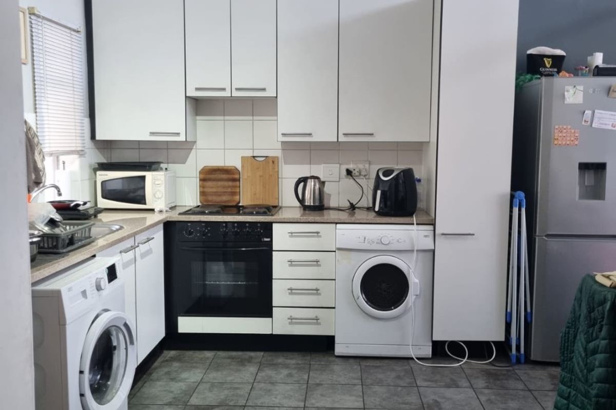 A functional kitchen featuring white cabinetry, tiled flooring, a built-in oven, and integrated laundry appliance connections.