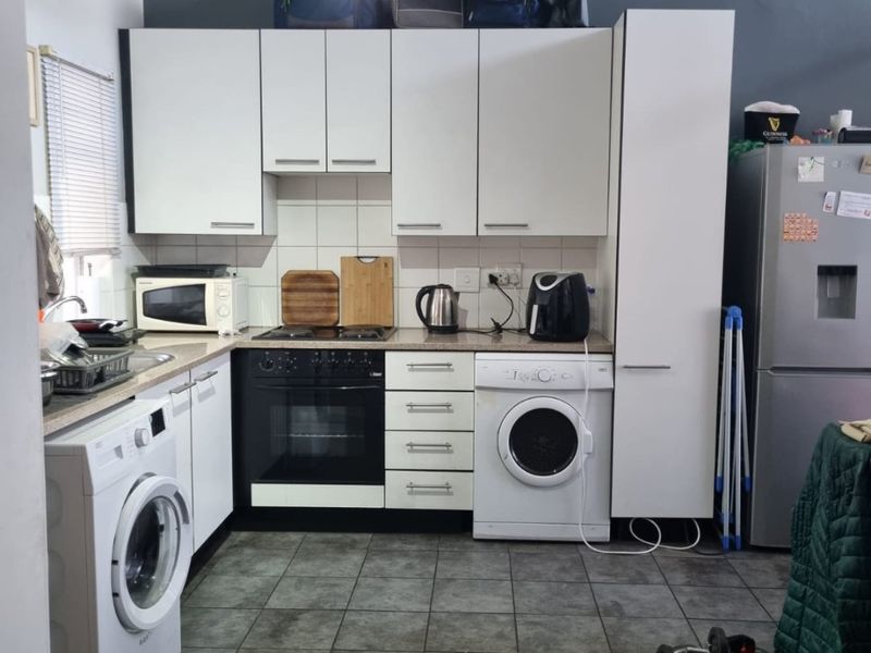 A functional kitchen featuring white cabinetry, tiled flooring, a built-in oven, and integrated laundry appliance connections.