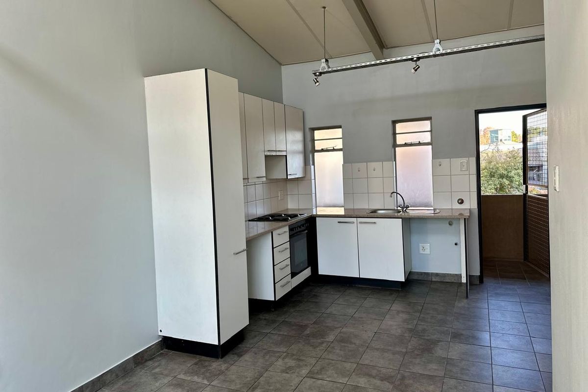 A functional kitchen featuring white built-in cabinetry, tiled flooring, and a built-in oven, offering a clean, blank canvas for potential modern updates.