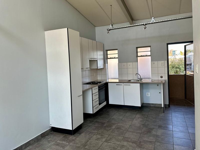 A functional kitchen featuring white built-in cabinetry, tiled flooring, and a built-in oven, offering a clean, blank canvas for potential modern updates.