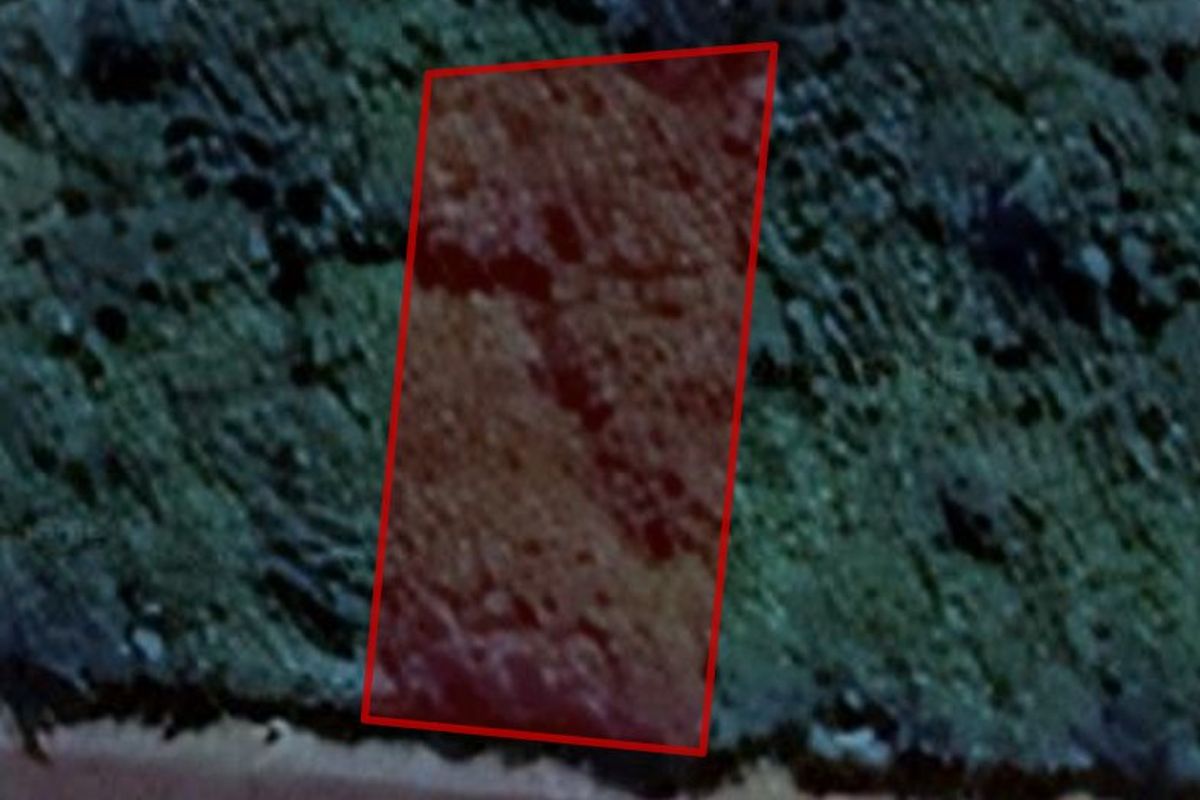 An aerial view of a vacant residential plot of land with a red boundary overlay indicating the property lines.