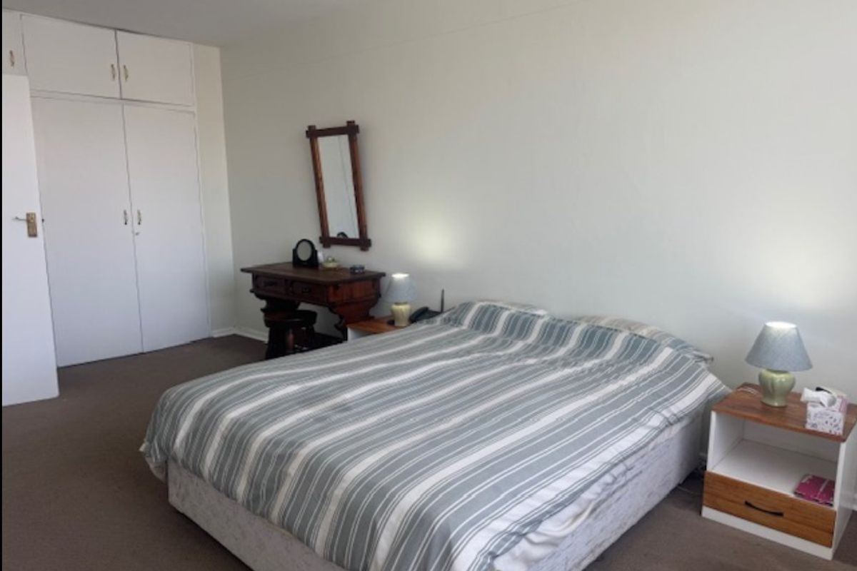 A bedroom featuring neutral wall finishes, carpeted flooring, and built-in cupboards for storage.
