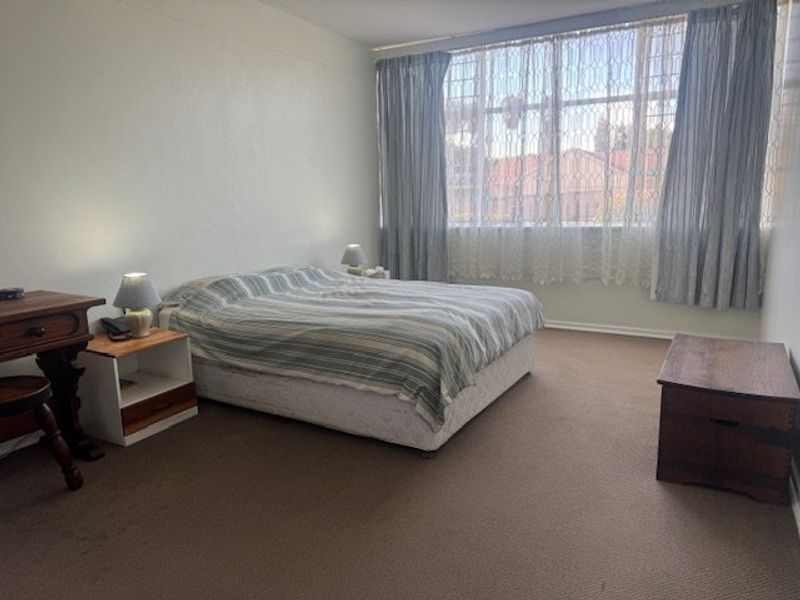 A spacious bedroom featuring large windows that provide ample natural light and neutral carpeted flooring throughout.
