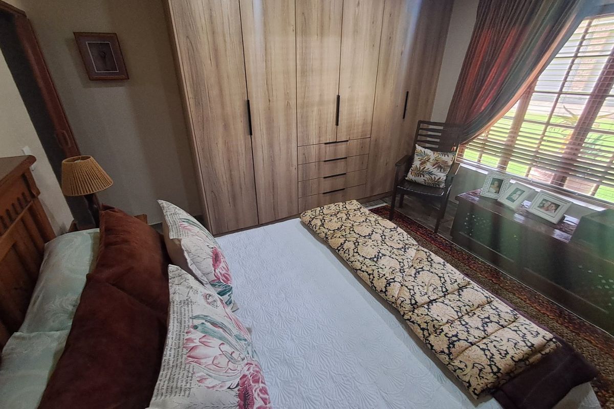 A well-maintained bedroom featuring extensive floor-to-ceiling built-in wooden cupboards and natural light through window blinds.