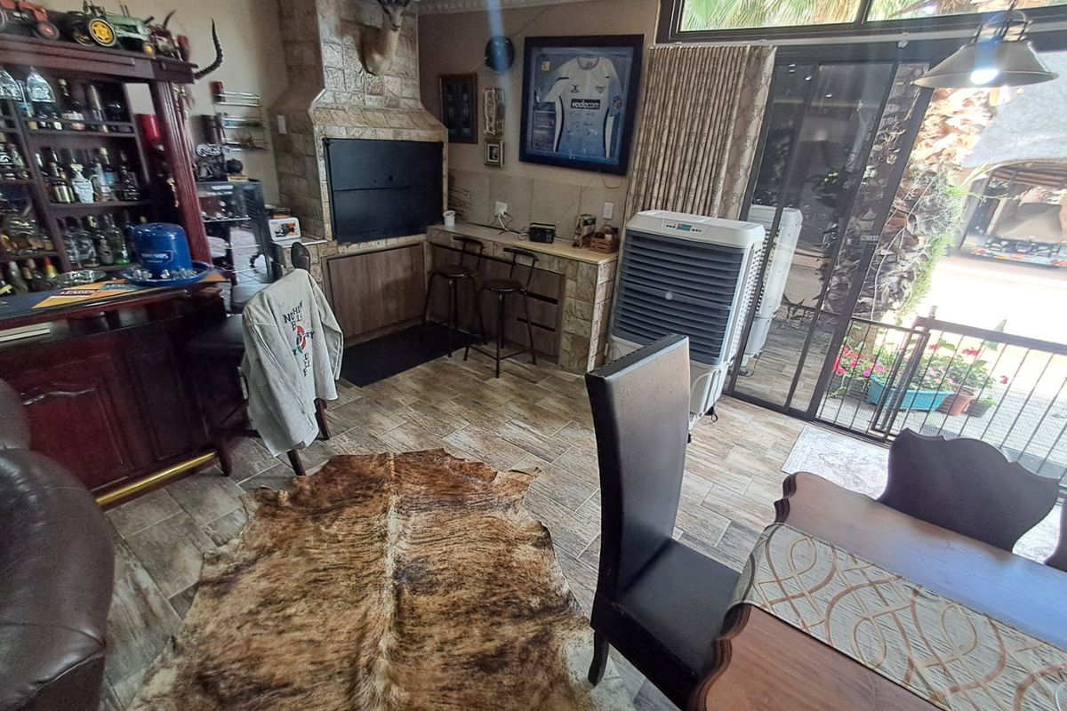 Living area featuring a built-in braai with stone cladding, tiled flooring, and large sliding glass doors providing access to the outdoor space.