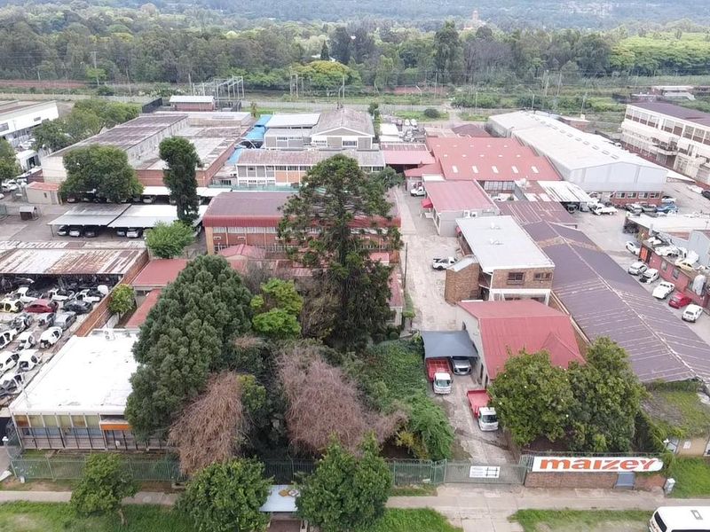 Aerial view of an industrial property complex featuring multiple warehouse structures, metal roofing, paved yard areas, and perimeter security fencing.