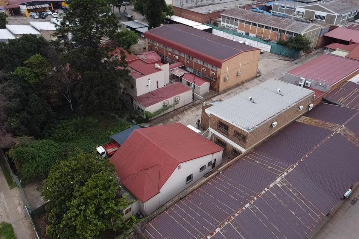 Aerial view of an industrial property complex featuring multiple buildings with metal roofing, brick facades, and paved access areas.