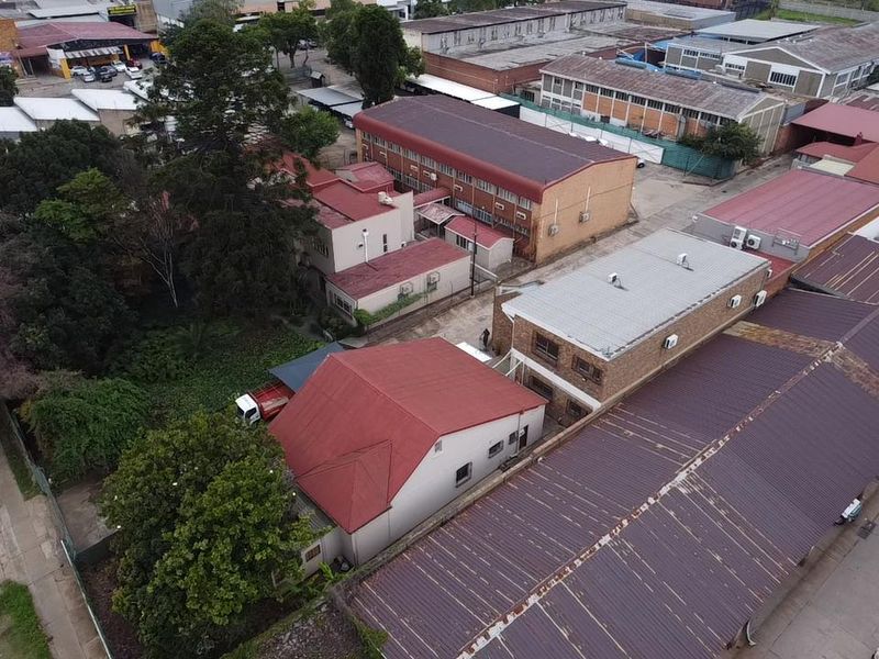 Aerial view of an industrial property complex featuring multiple buildings with metal roofing, brick facades, and paved access areas.