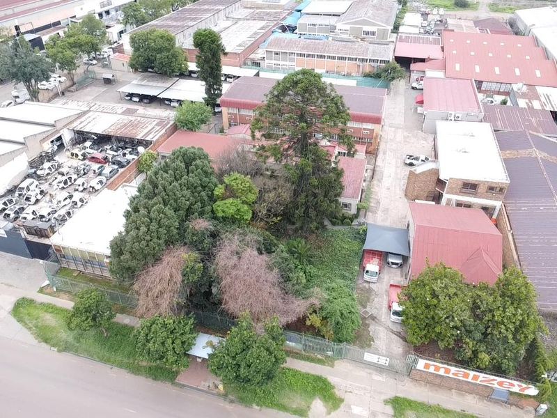 Aerial view of an industrial property complex featuring multiple warehouse structures, paved access areas, and established landscaping.