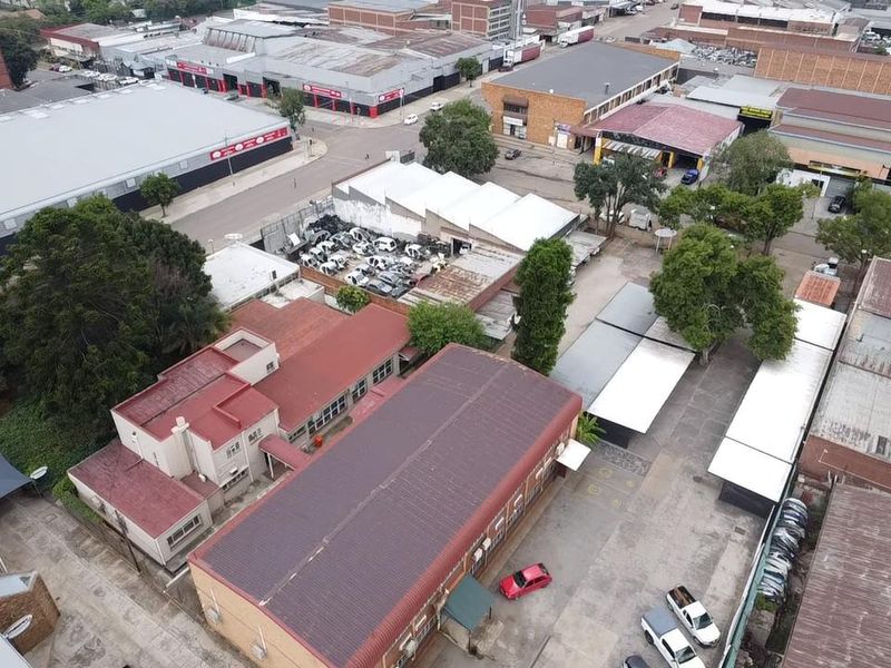 Aerial view of an industrial property complex featuring multiple warehouse buildings, paved yard space, and covered parking areas within an established industrial precinct.