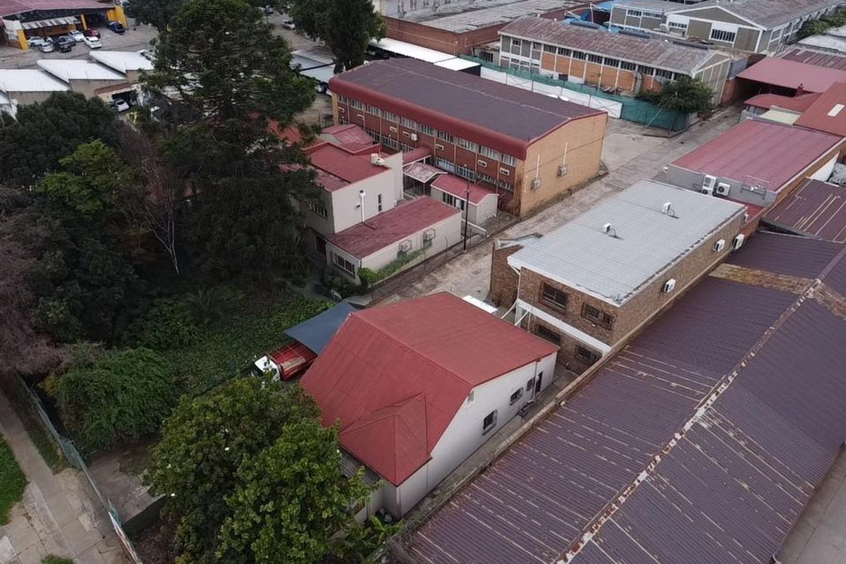 Aerial view of an industrial property complex featuring multiple buildings with metal roofing, brick facades, and integrated air conditioning units.