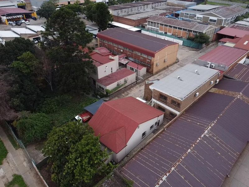 Aerial view of an industrial property complex featuring multiple buildings with metal roofing, brick facades, and integrated air conditioning units.