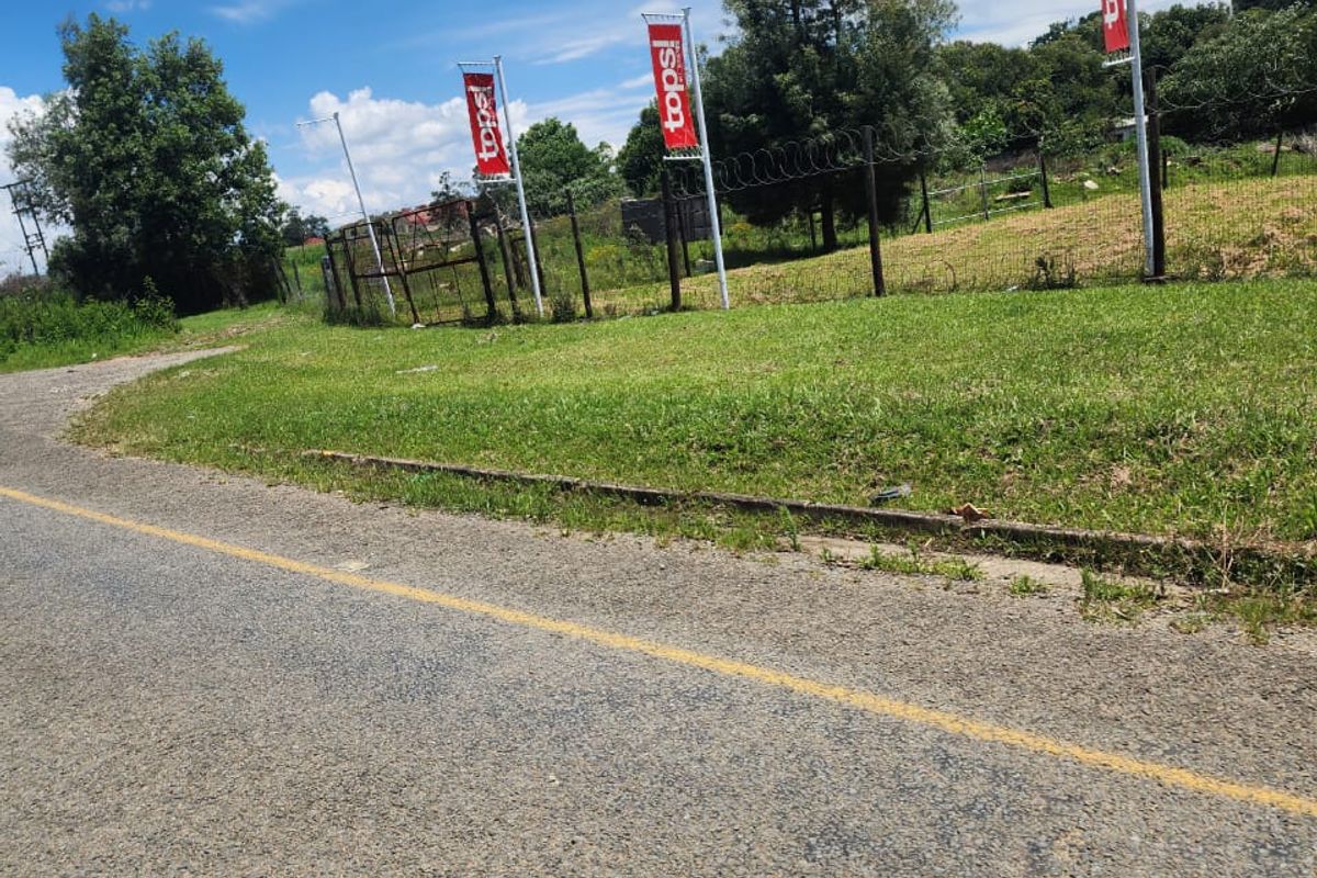 Street view of a vacant residential plot featuring perimeter fencing with razor wire and roadside access.