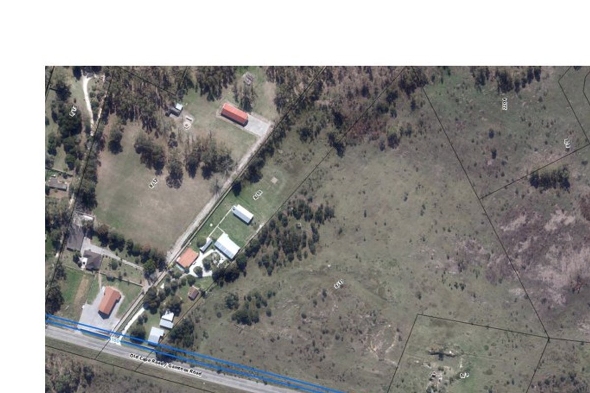 An aerial view showing the land parcel boundaries and surrounding landscape, including nearby structures and road access.
