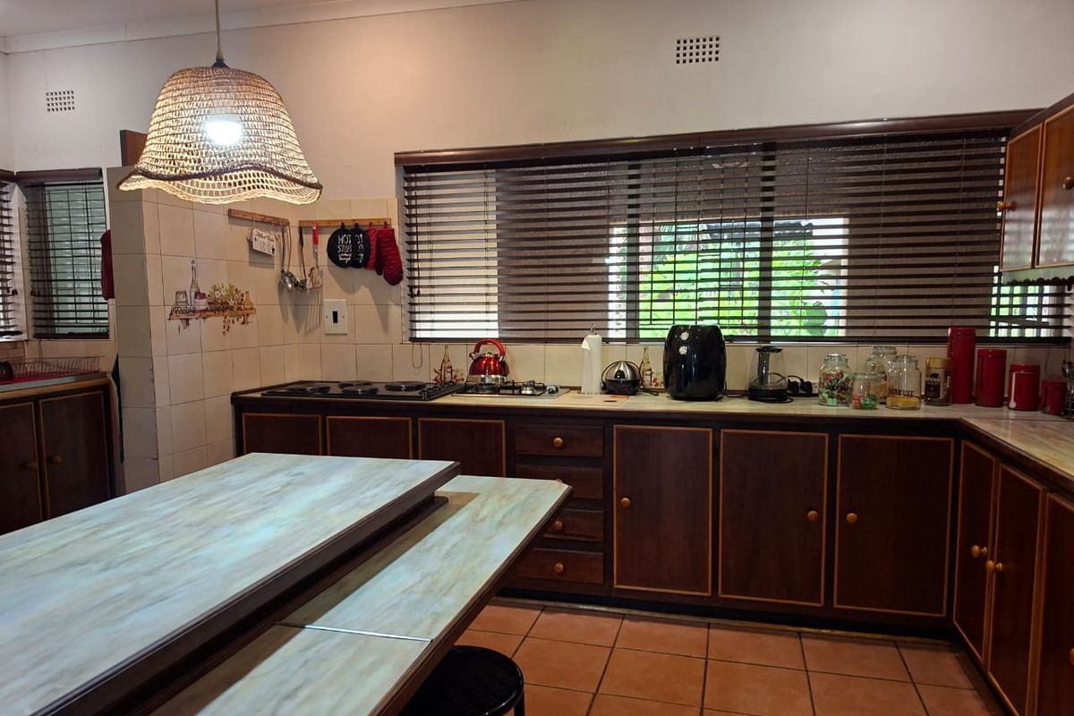 A functional kitchen featuring dark wood cabinetry, tiled countertops, a built-in gas hob, and terracotta floor tiles.