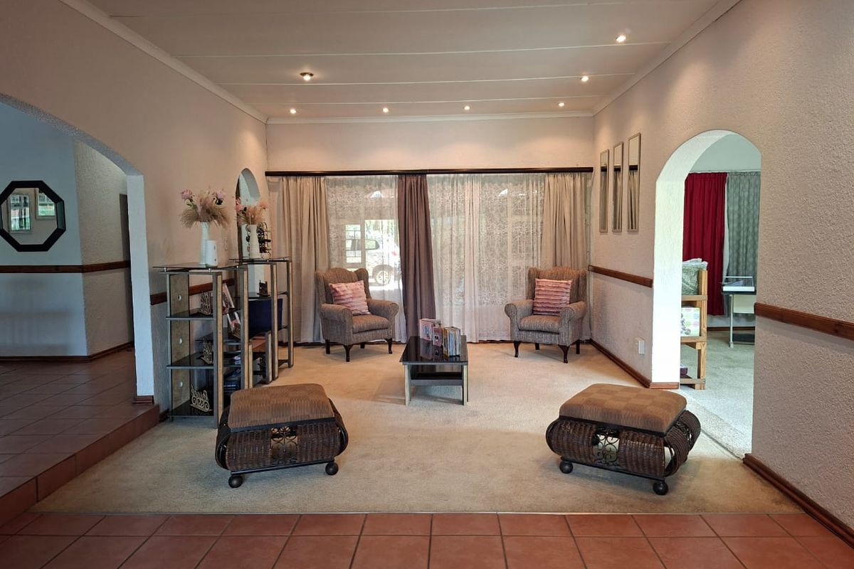 A spacious living room featuring arched entryways, recessed ceiling lighting, and neutral carpeting, providing a comfortable and well-defined area for relaxation.