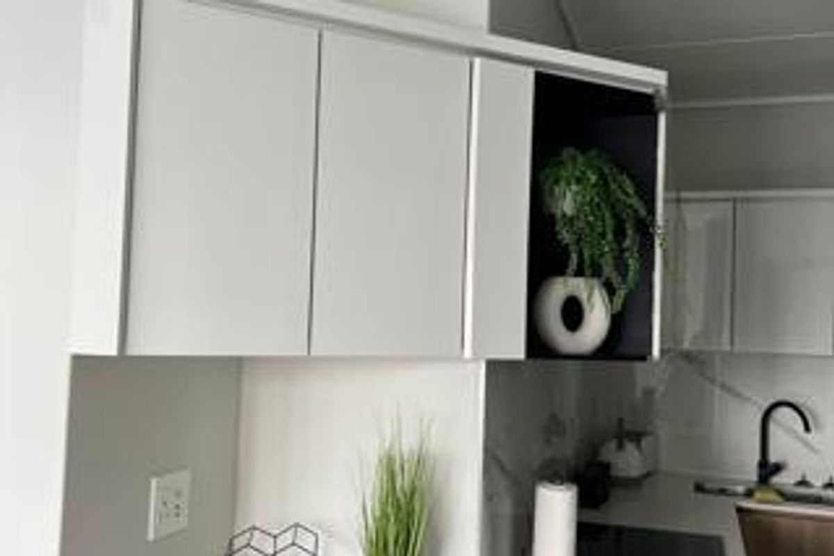 Modern kitchen featuring sleek white cabinetry, contrasting black open shelving, and a contemporary sink with a black mixer tap.
