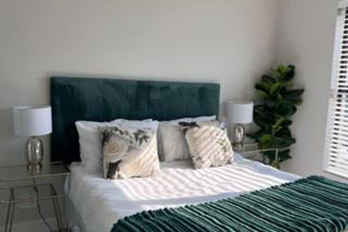 A well-maintained bedroom featuring neutral walls and venetian blinds, providing a clean and comfortable living space.