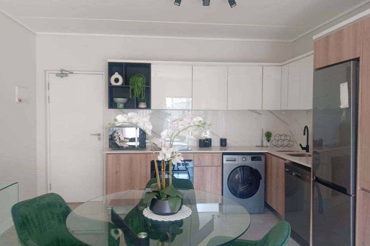Modern kitchen featuring sleek white and wood-tone cabinetry, marble-look splashback, integrated appliances, and contemporary track lighting in an open-plan layout.