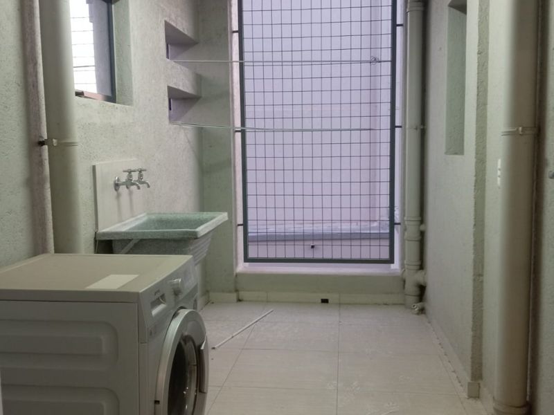 A functional laundry area featuring a utility sink, tiled flooring, and a security-grille window, providing a practical space for washing and utility tasks.
