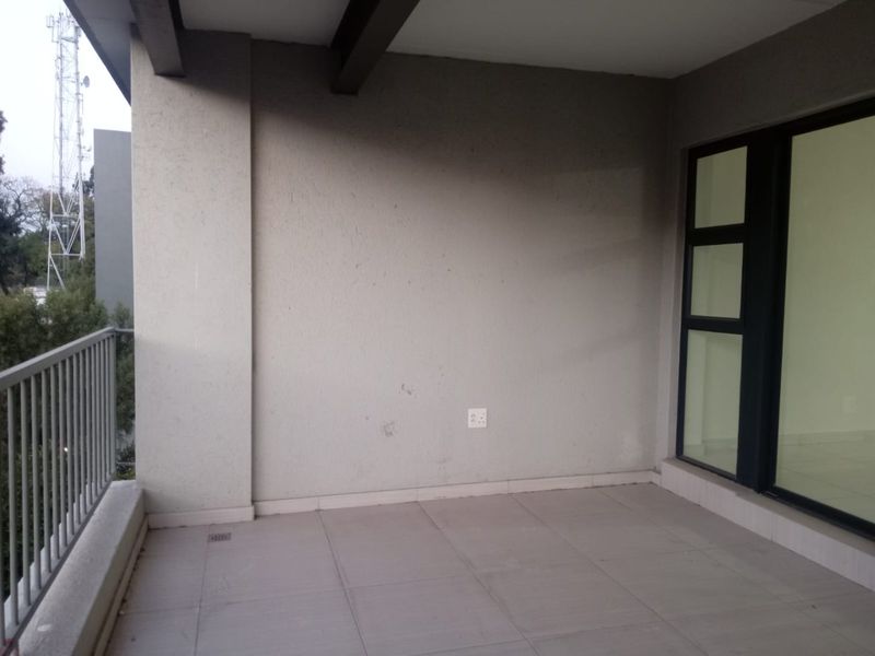 A covered balcony featuring tiled flooring, a metal balustrade, and a large sliding glass door providing access to the interior.