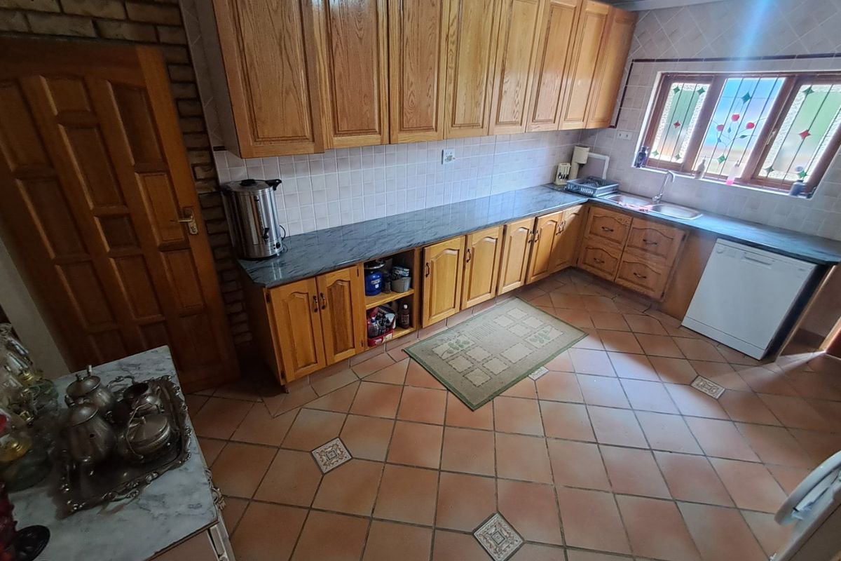 A traditional kitchen featuring wooden cabinetry, tiled flooring, and a leaded glass window, offering a functional layout with ample storage space.