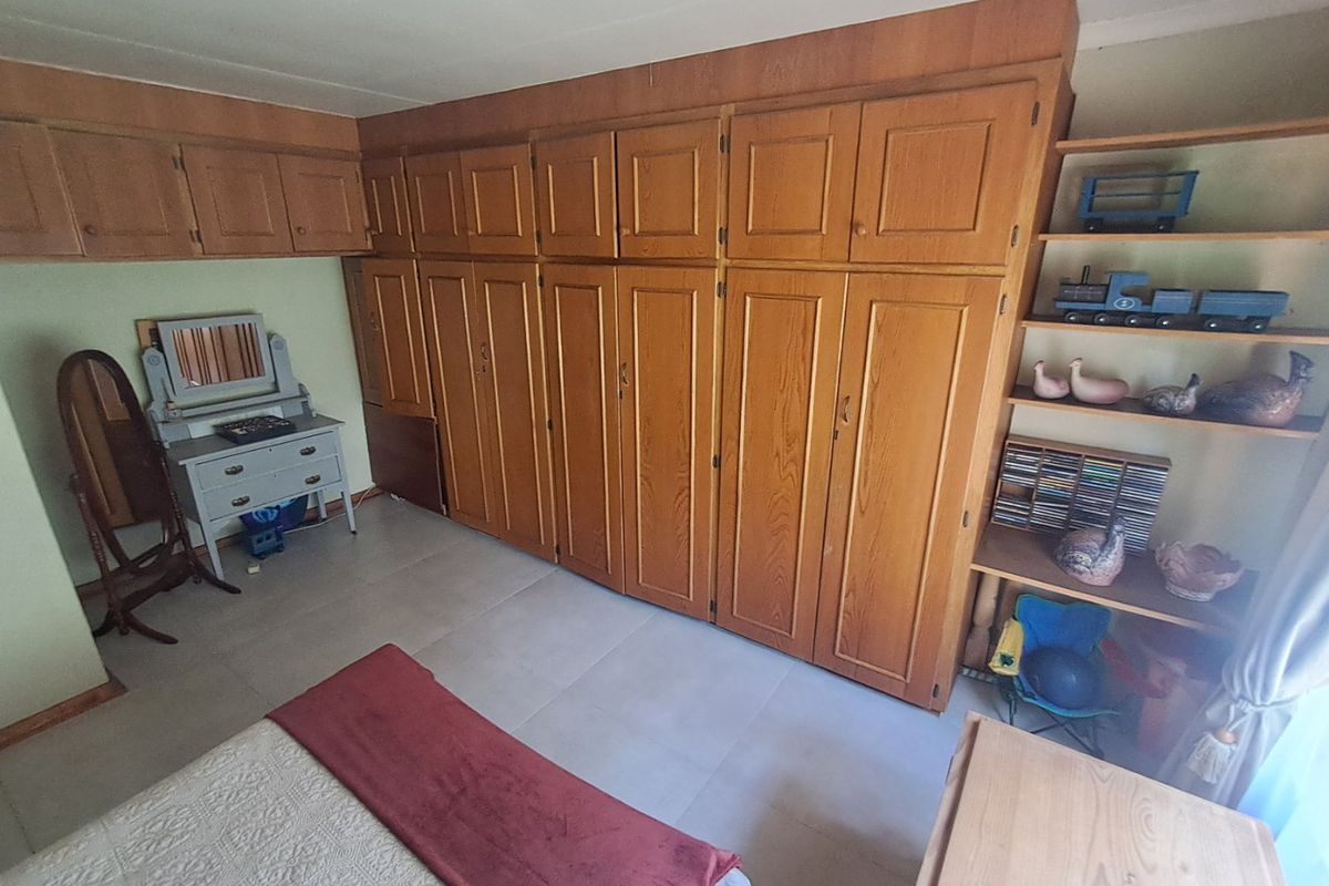A bedroom featuring extensive wall-to-wall built-in wooden cabinetry and tiled flooring, offering ample storage space.