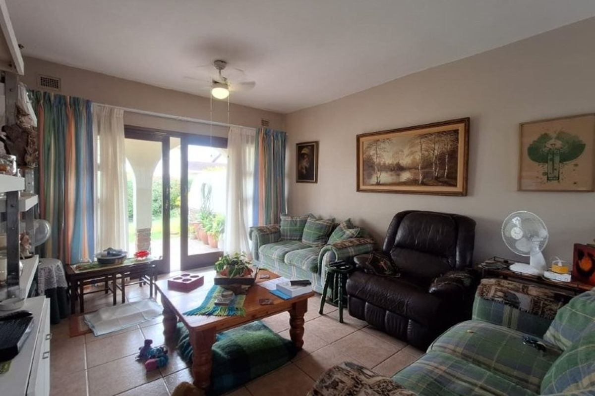 A comfortable living room featuring tiled flooring, a ceiling fan, and a sliding glass door providing access to the outdoor patio area.