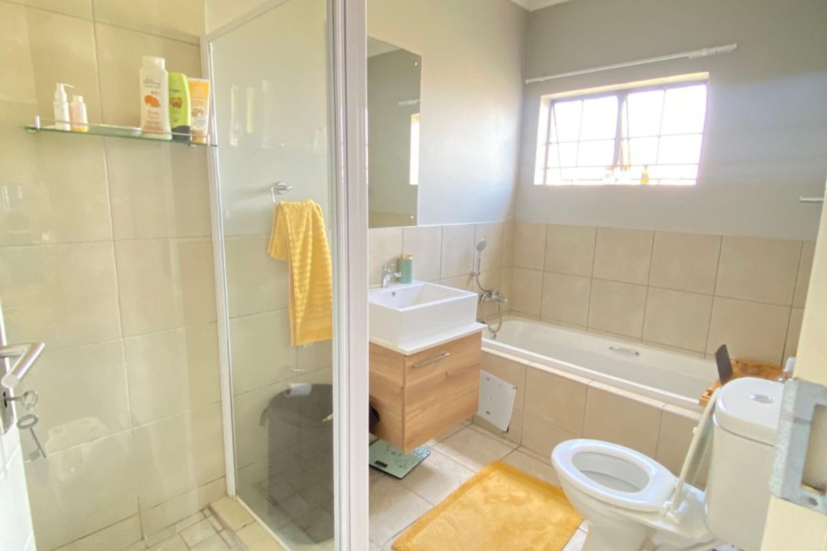 A functional bathroom featuring a separate shower enclosure, bathtub, vanity with vessel sink, and tiled finishes throughout.