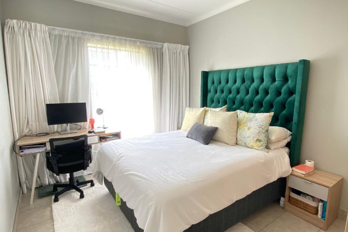 A well-lit bedroom featuring neutral wall tones, tiled flooring, and a modern ceiling-mounted spotlight fixture.