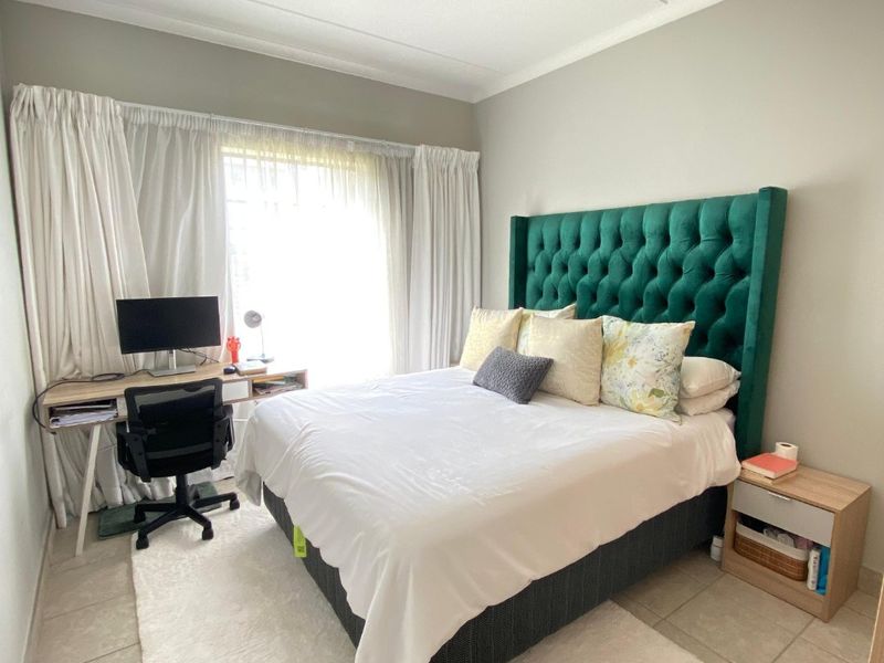 A well-lit bedroom featuring neutral wall tones, tiled flooring, and a modern ceiling-mounted spotlight fixture.