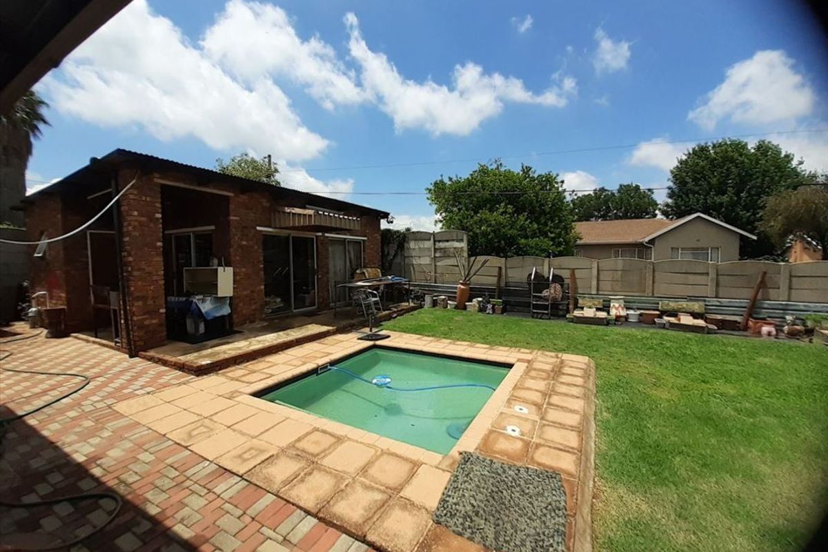 Rear garden area featuring a swimming pool, brick paved patio, and exposed brick building facade with sliding door access.