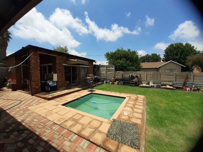 Rear garden area featuring a swimming pool, brick paved patio, and exposed brick building facade with sliding door access.