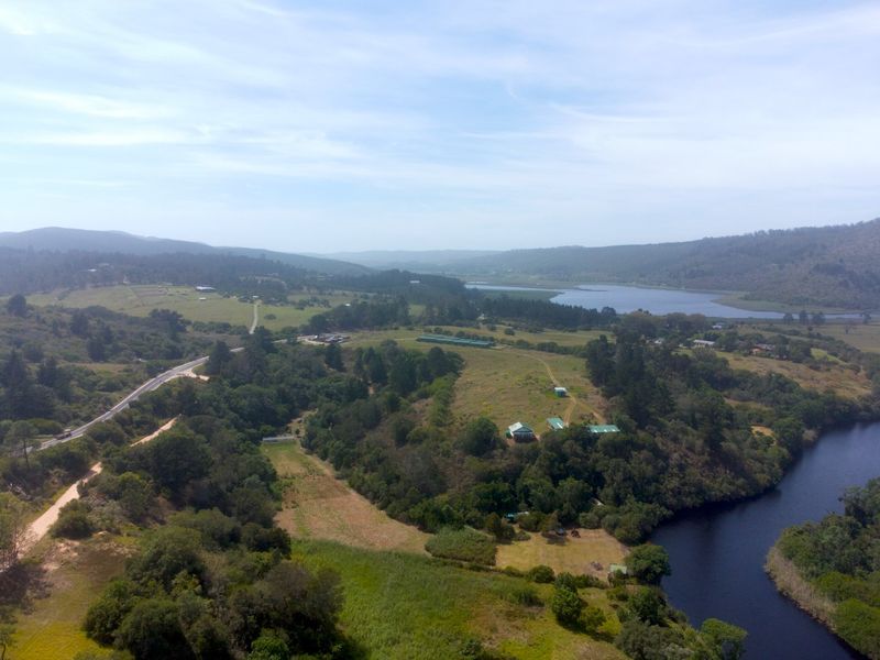 An aerial view of the expansive farm property featuring natural river frontage, surrounding hills, and established farm infrastructure.