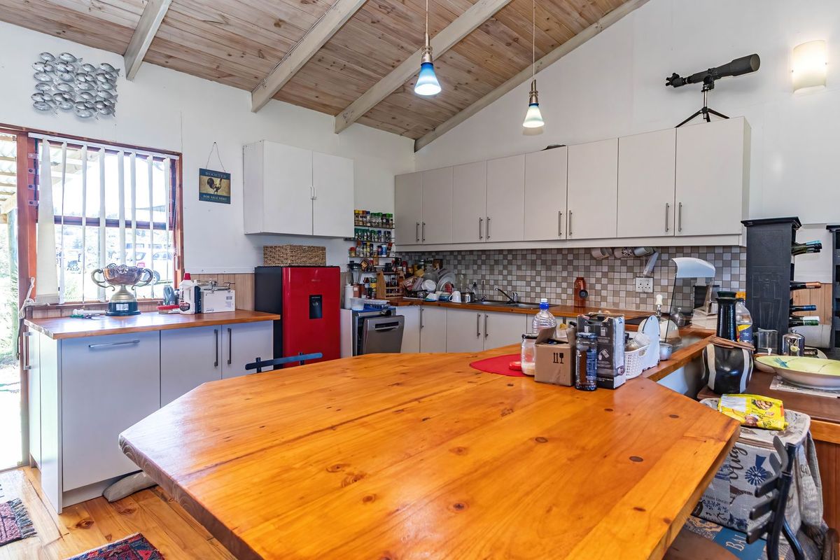 A rustic kitchen featuring exposed wooden beam ceilings, ample built-in cabinetry, a large wooden breakfast bar, and a tiled backsplash.