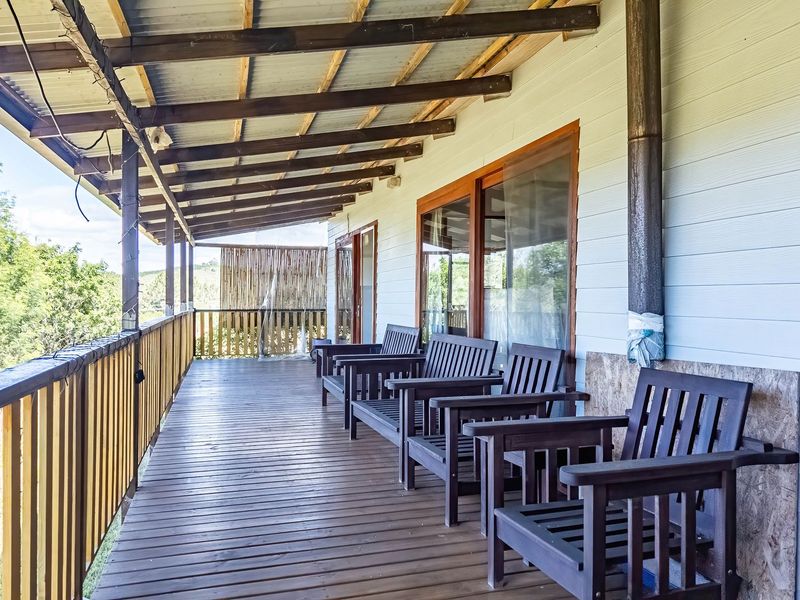 A covered timber deck patio featuring exposed rafters, wooden balustrades, and sliding glass door access to the main dwelling.