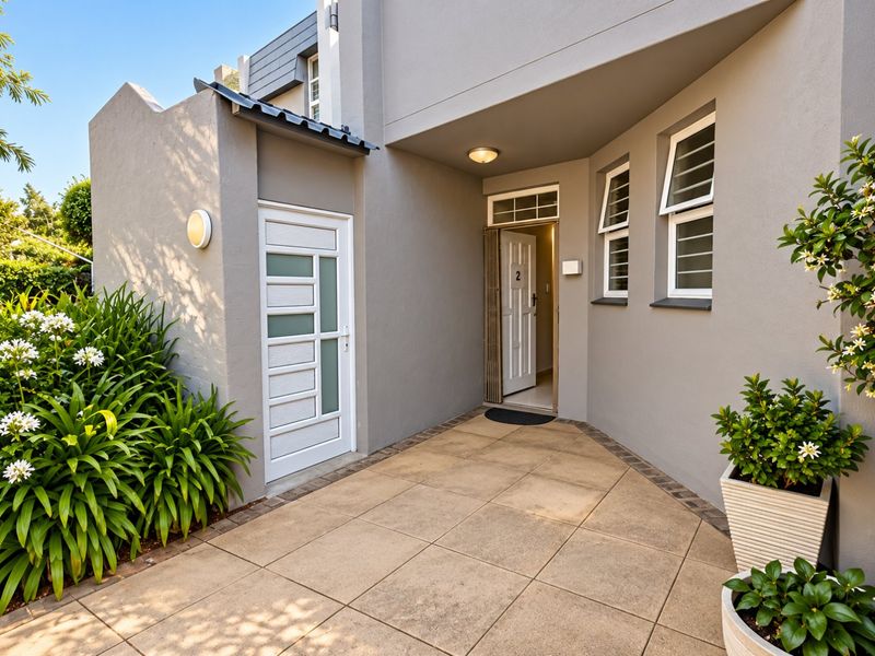 A well-maintained front entrance area featuring a tiled patio, secure front door, and modern exterior lighting, providing a welcoming approach to the townhouse.